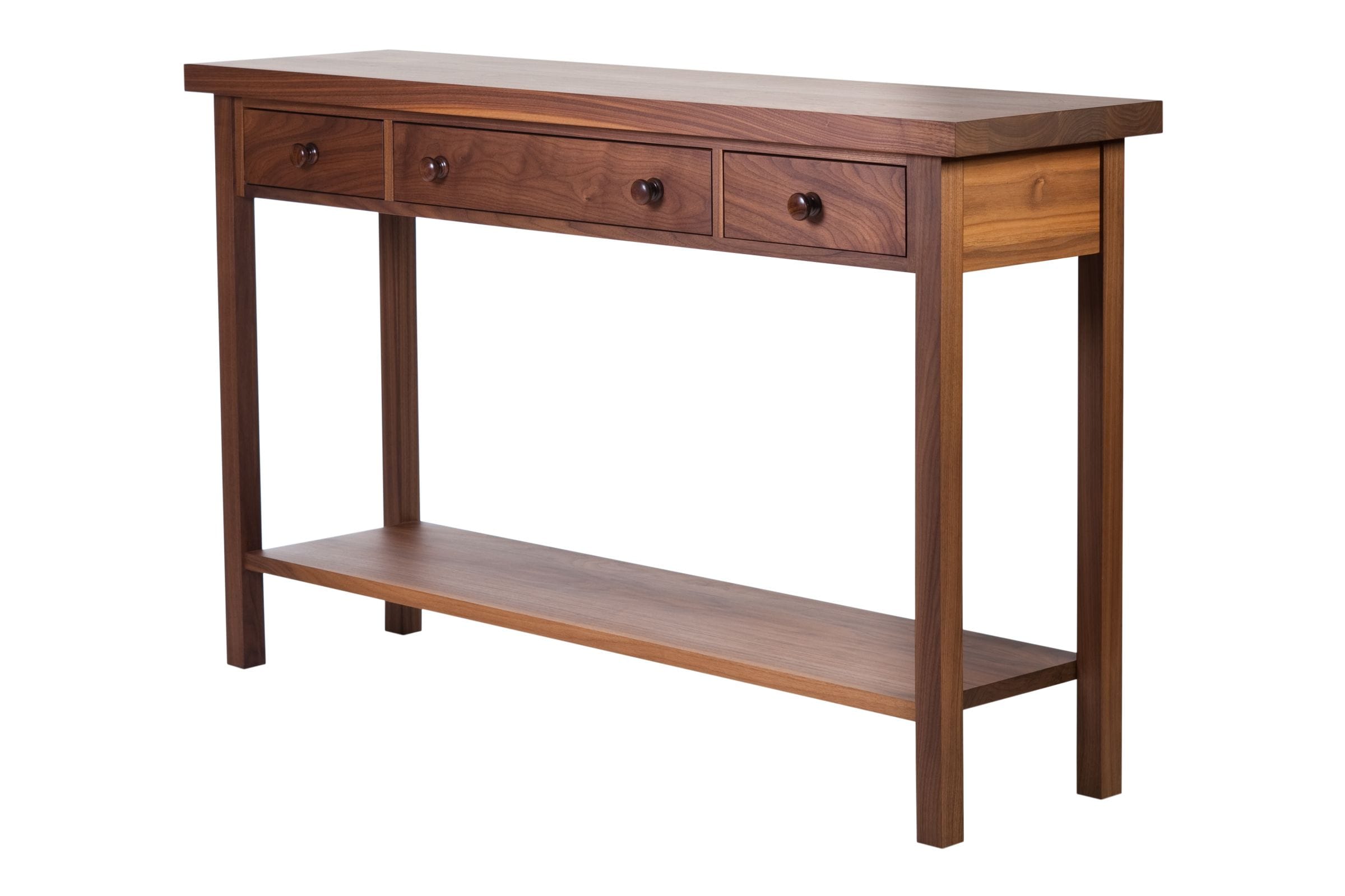 Angled view of a three-drawer walnut console table with lower display shelf