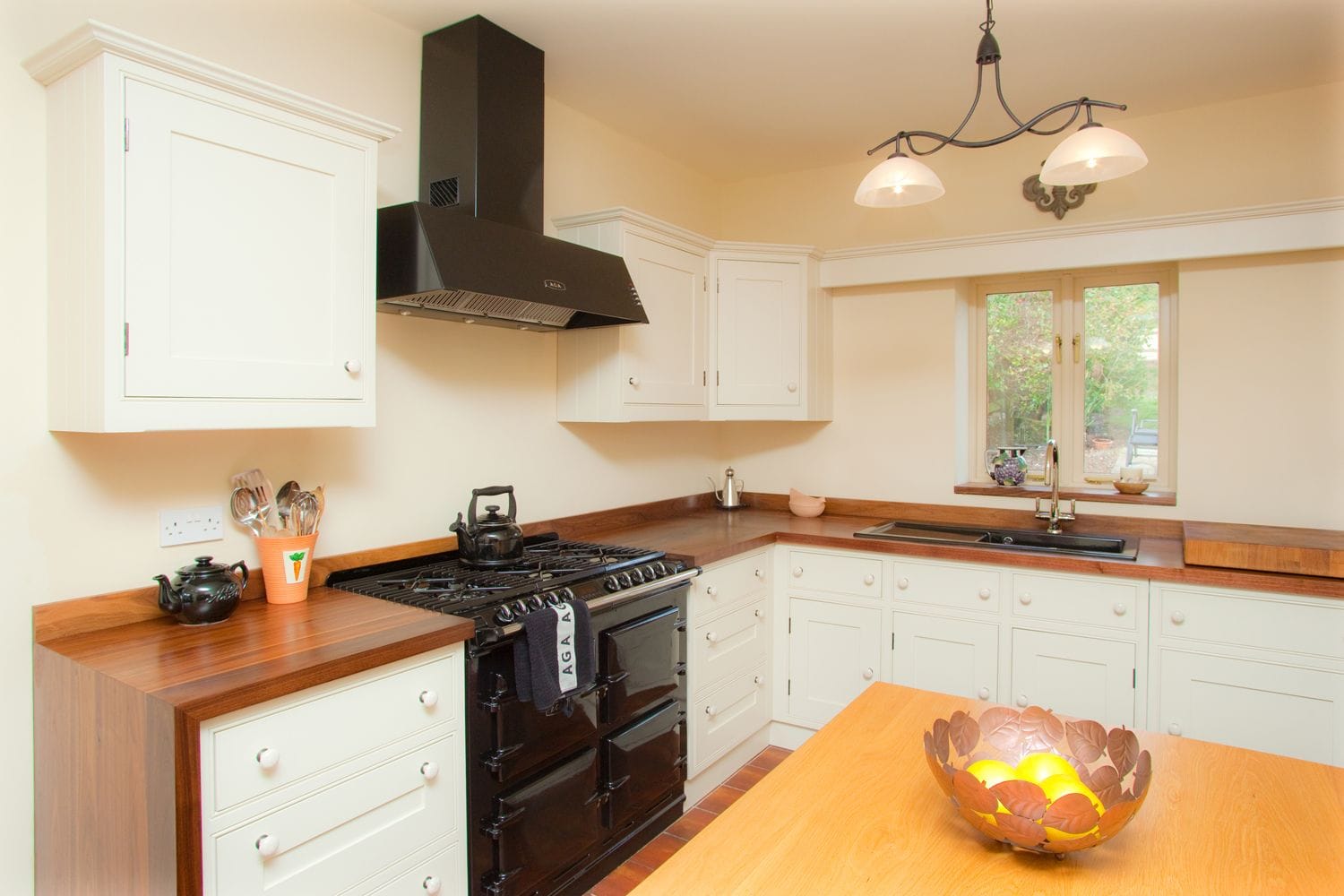 Cream country kitchen with black Aga and dark wood worktops around the range