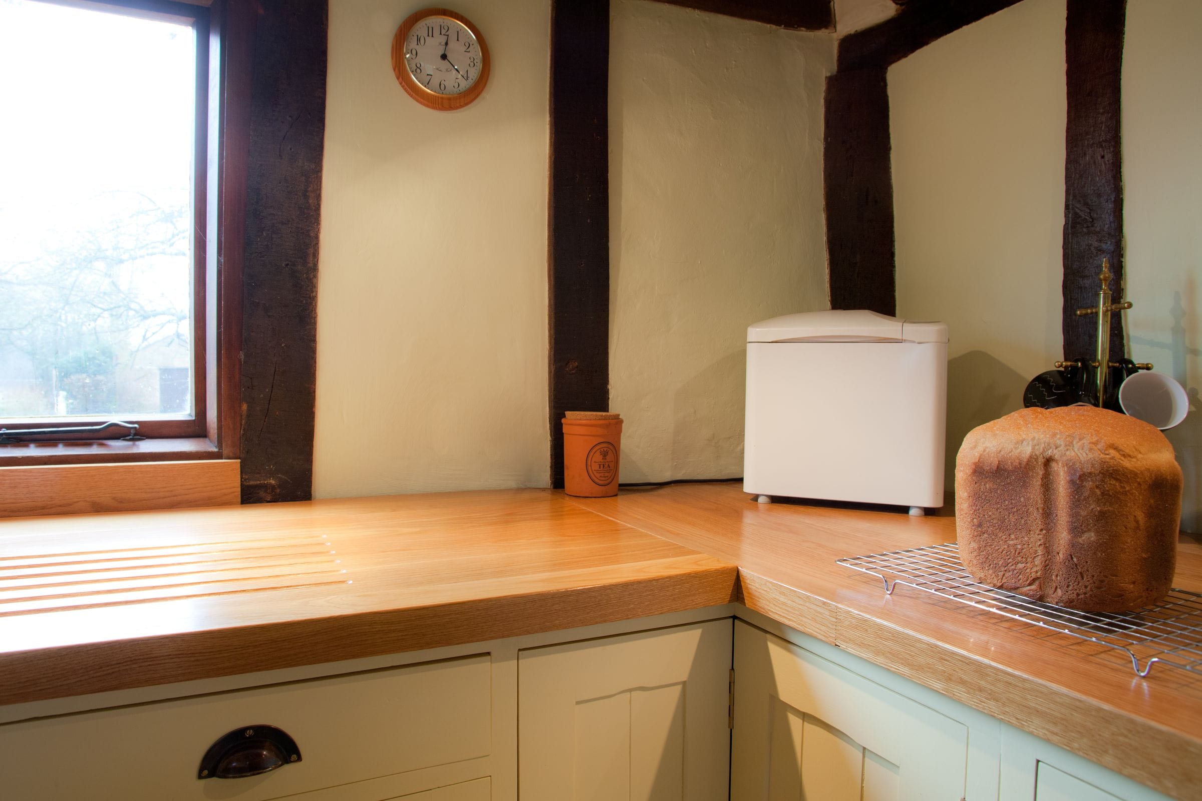 Oak worktops with carved draining grooves in a beamed cottage kitchen