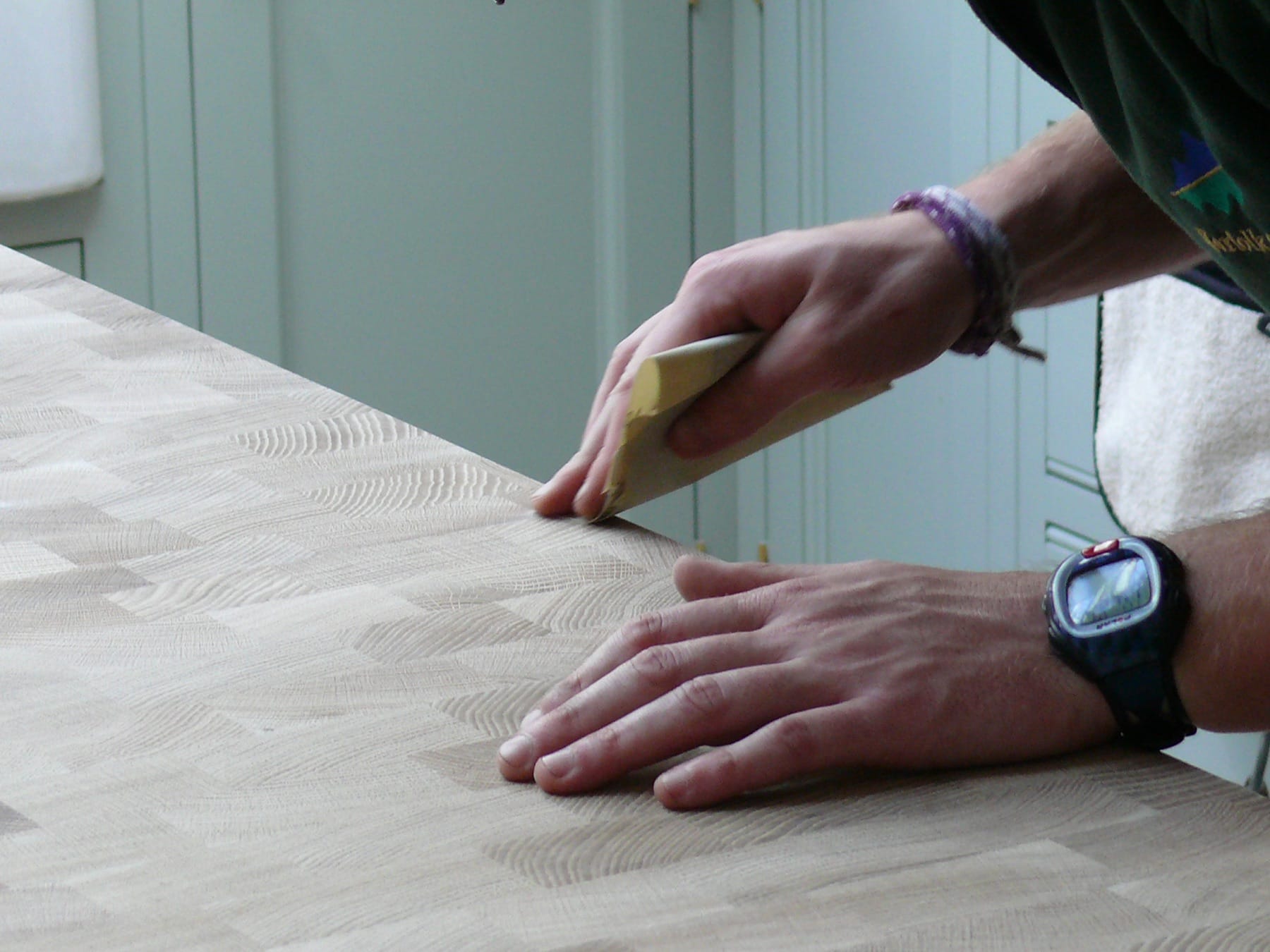 Hand-sanding the end-grain surface of a wooden worktop with a sanding block
