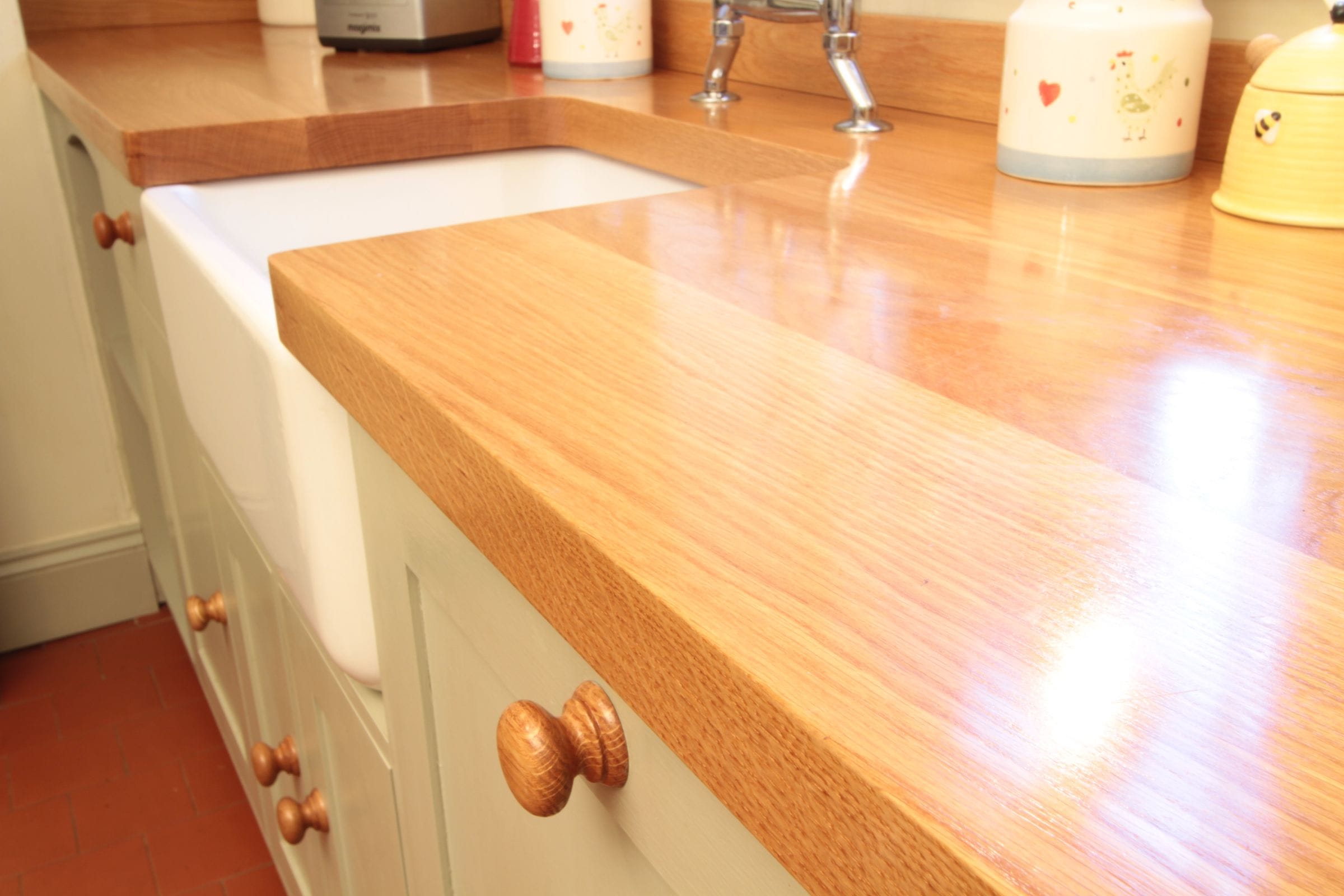 Oiled oak worktop edge above a white Belfast sink and cream painted cabinets