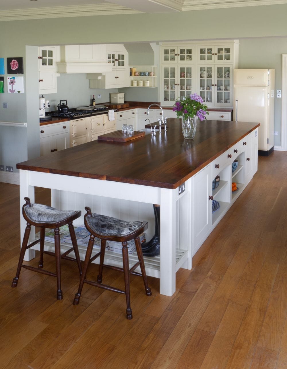 Country kitchen island with walnut worktop and two saddle-seat stools