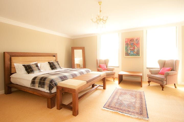 Bedroom with solid wood bed frame, matching bench and two armchairs