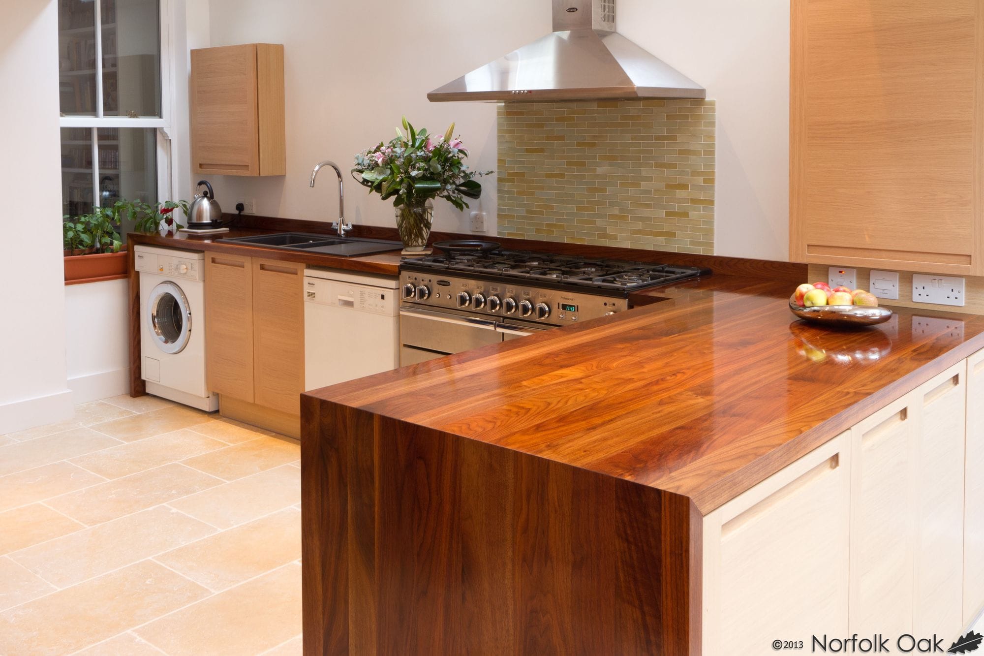 Kitchen with polished walnut breakfast bar with waterfall end panel and range cooker beyond