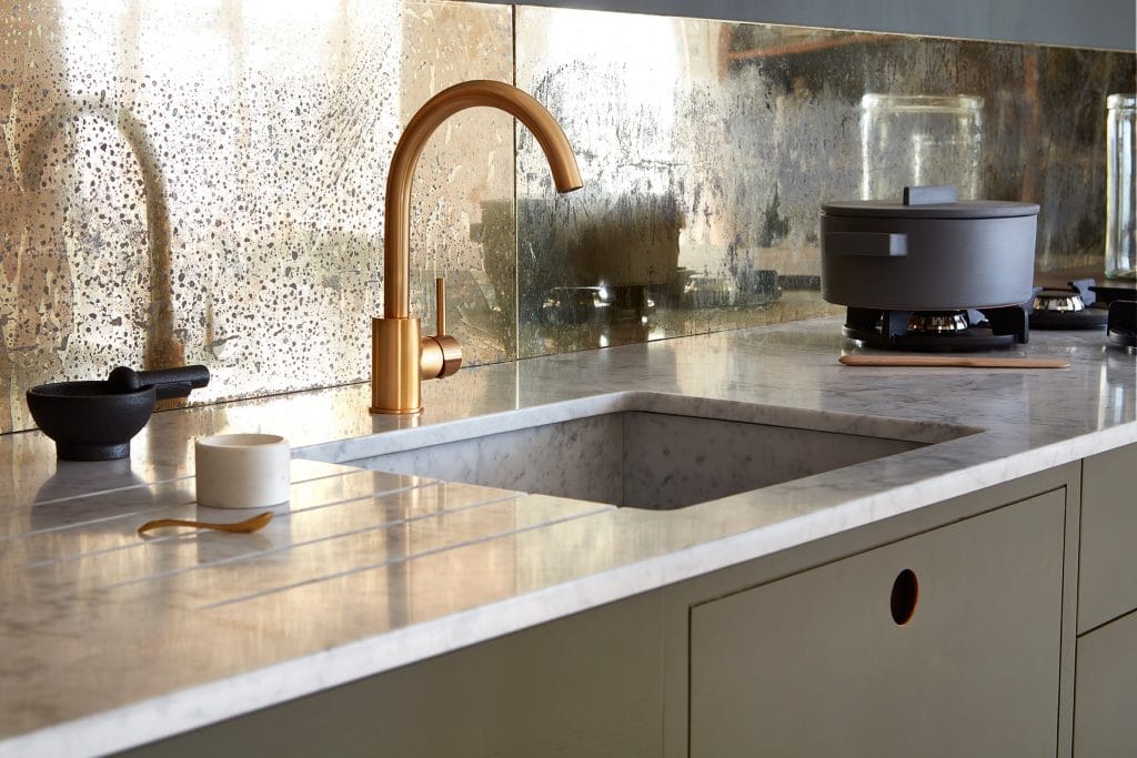 Marble worktop with drainer grooves, brass tap and antique mirrored splashback