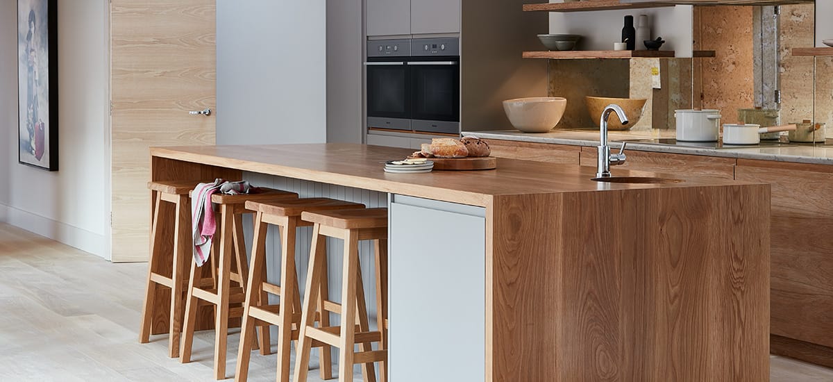 Oak super stave worktop on a kitchen island with matching stools, inset sink and tap