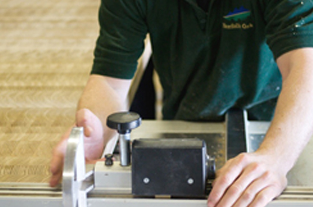 Machinist guiding timber through a workshop machine, close up