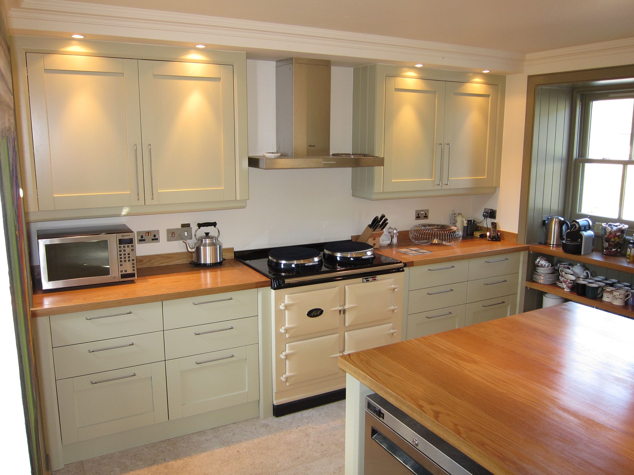 Sage green kitchen with oak worktops, cream Aga and oak-topped island