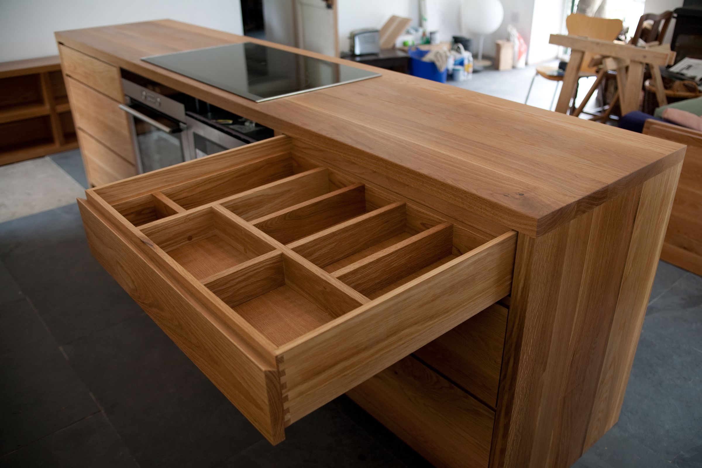 Open dovetailed oak cutlery drawer in a solid oak kitchen island with hob