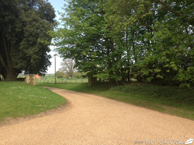 Gravel driveway curving past lawns and mature trees at Anmer Hall