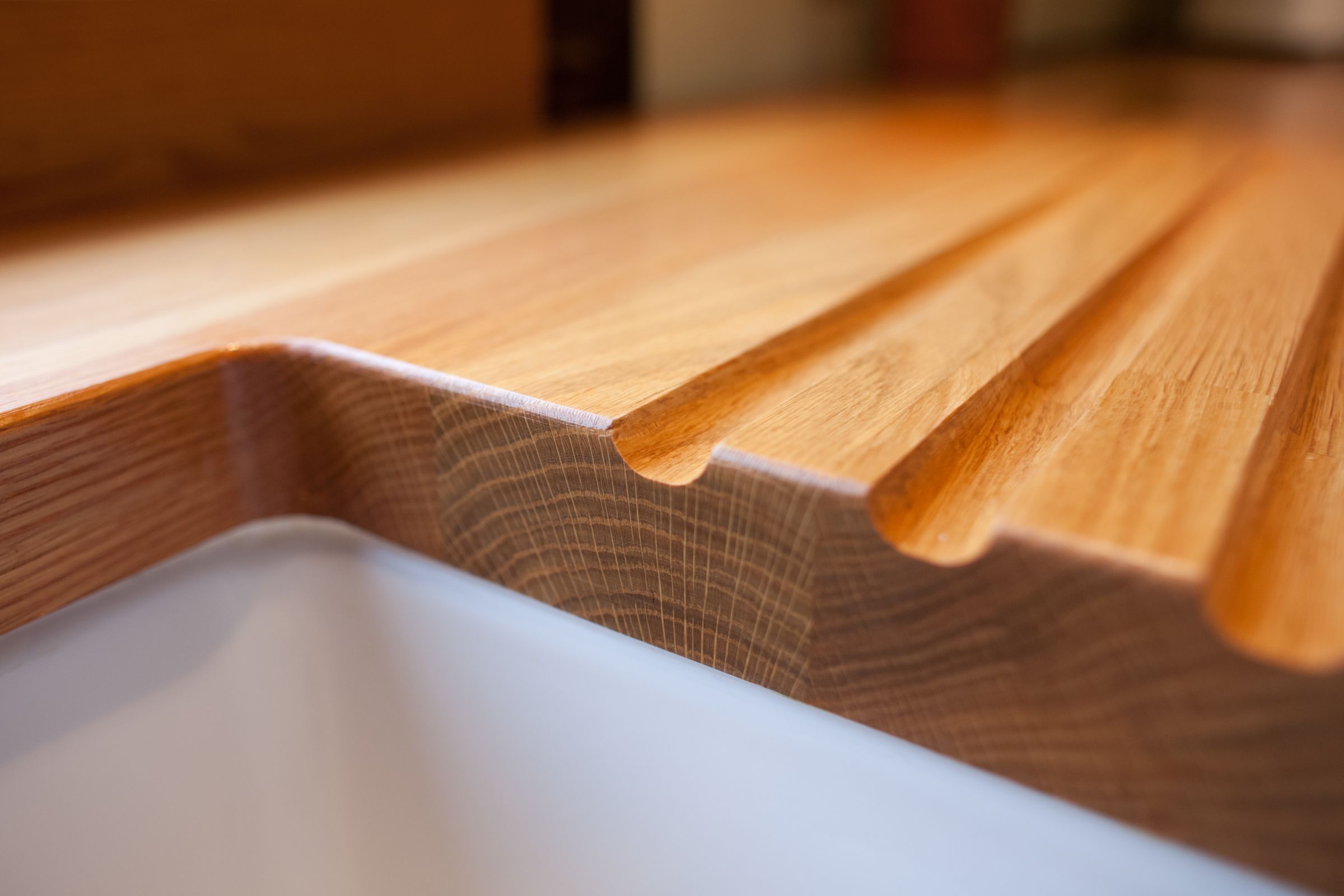 oak worktops Close-up of draining grooves carved into an oak worktop above a white ceramic sink
