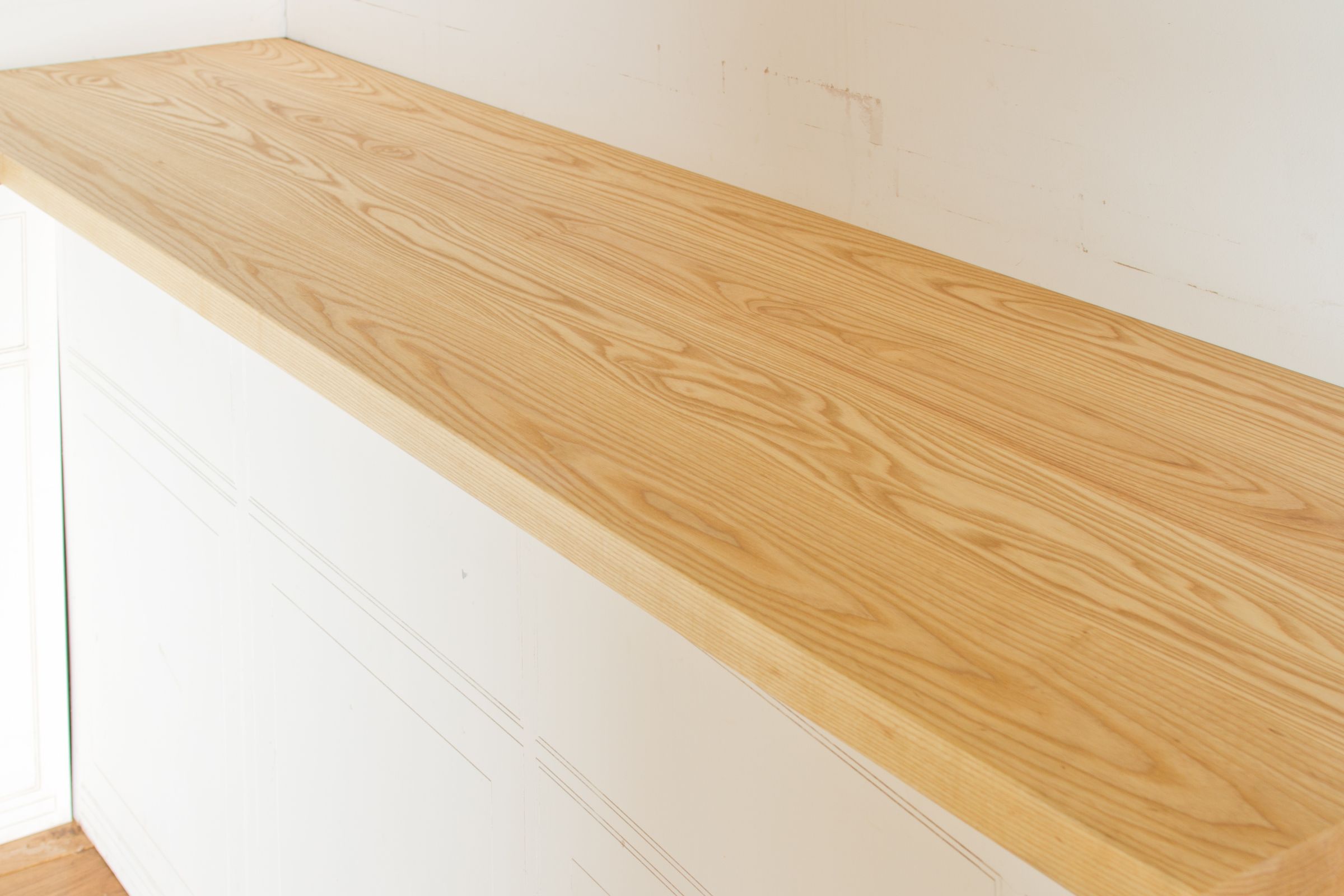 Pale American ash worktop with flowing grain on white painted cabinets