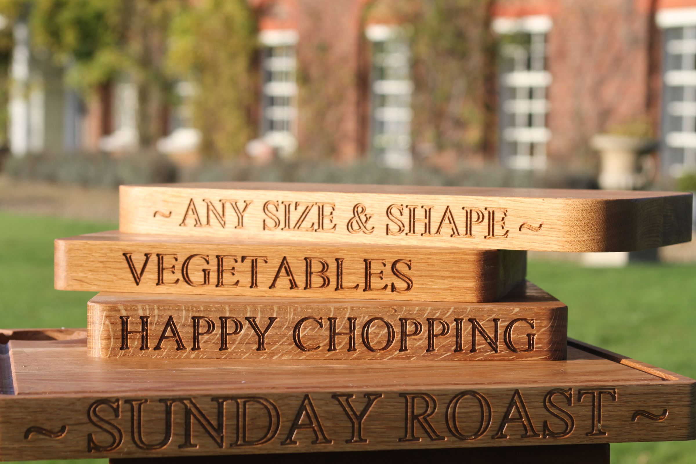 Stacked oak chopping boards engraved with phrases including Happy Chopping and Sunday Roast