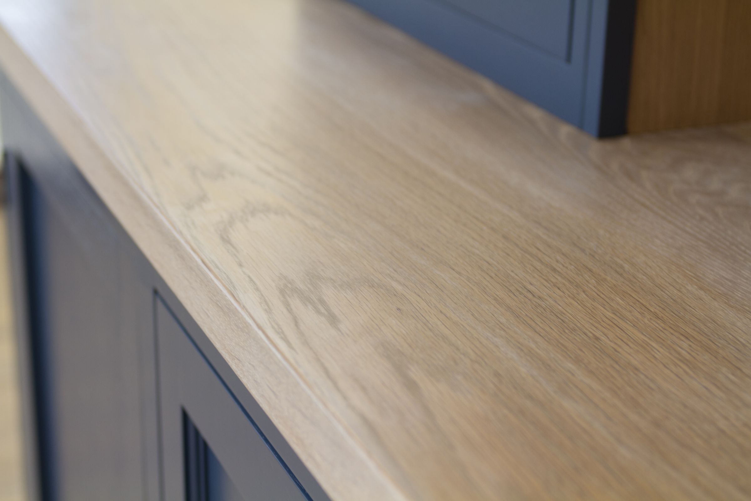Whitewashed oak worktop surface above dark blue showroom cabinetry