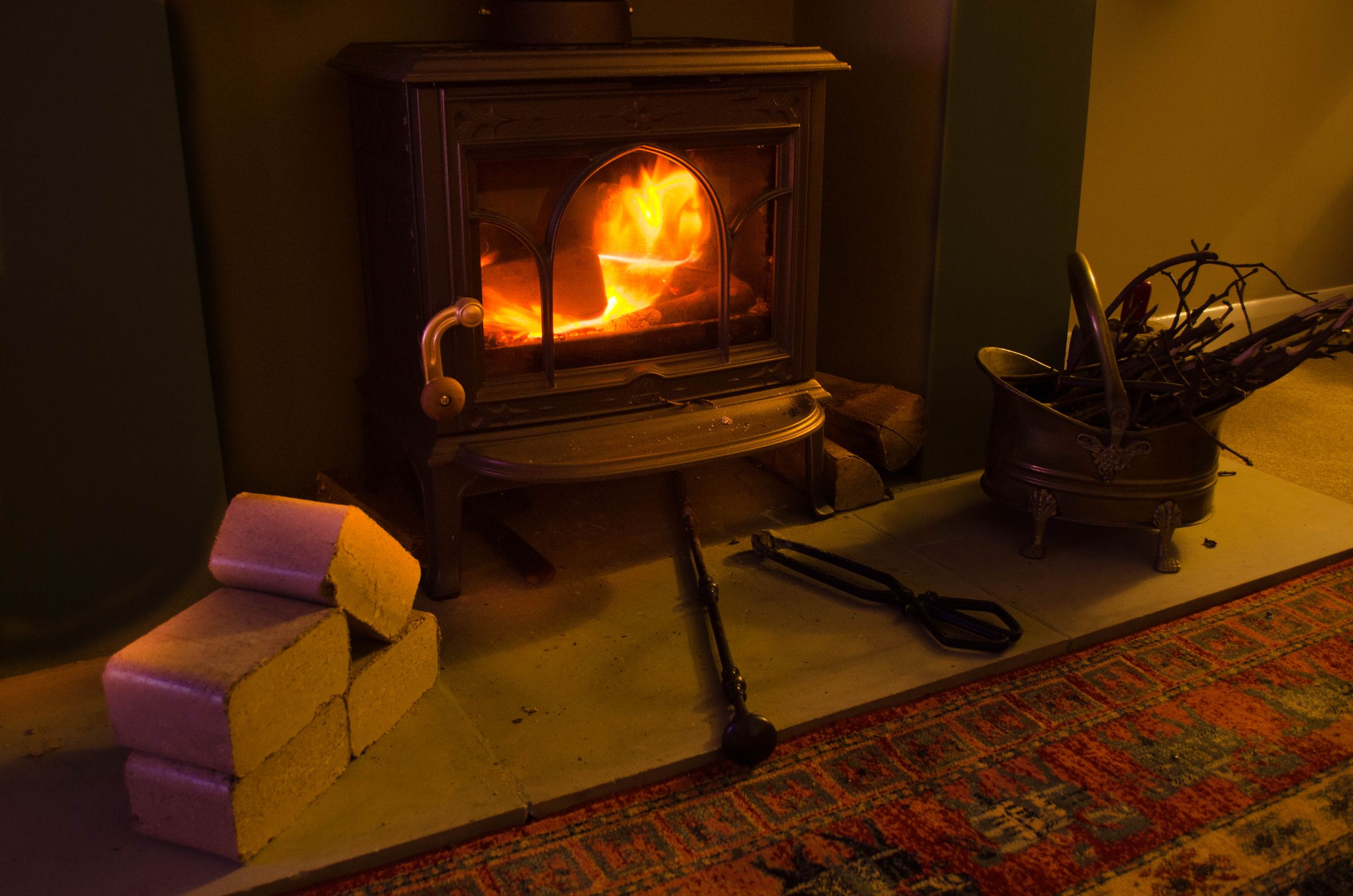 hardwood briquettes Stack of hardwood briquettes on the hearth in front of a lit wood-burning stove