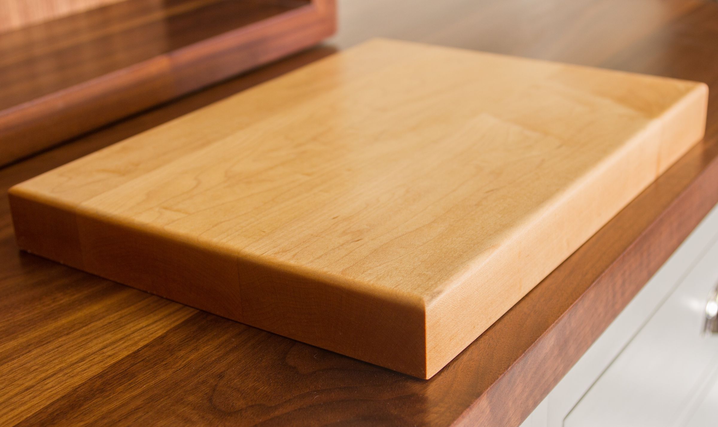 Thick maple chopping board with rounded edges on a walnut worktop