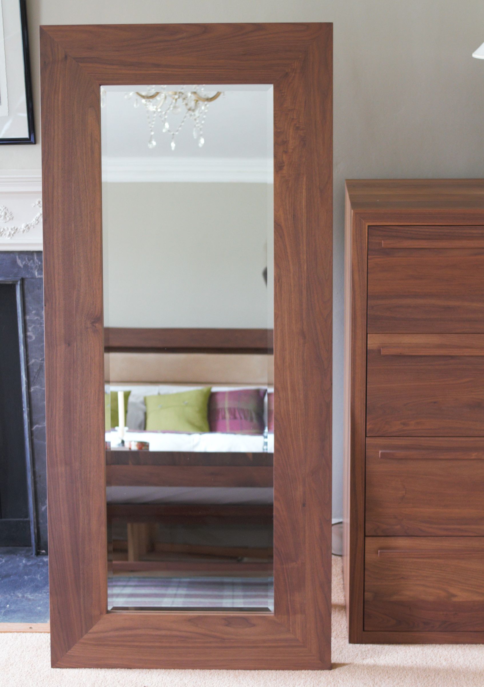 Tall freestanding walnut-framed mirror leaning beside a matching chest of drawers