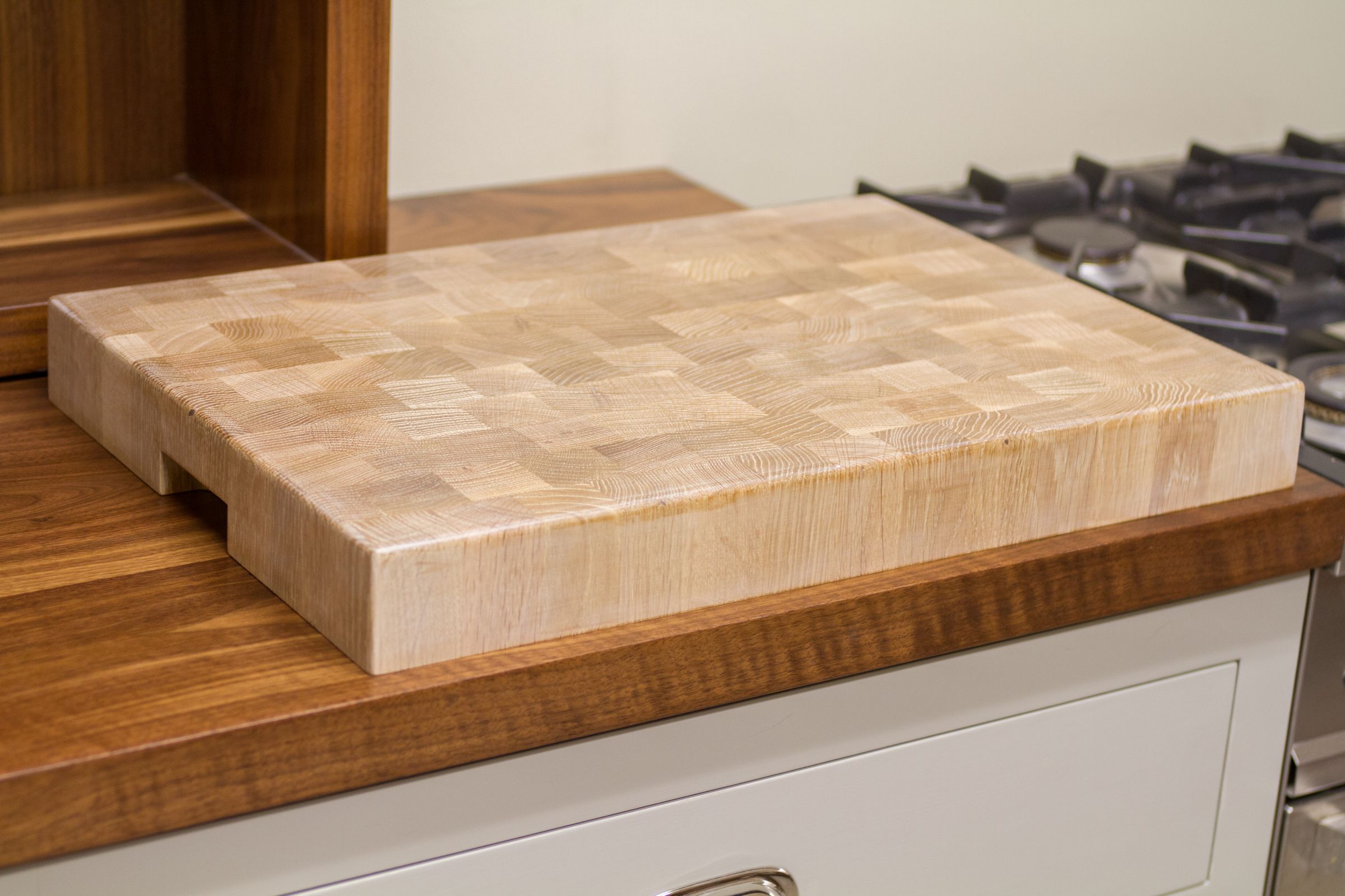Whitewashed oak end grain chopping block on a walnut worktop beside a gas hob