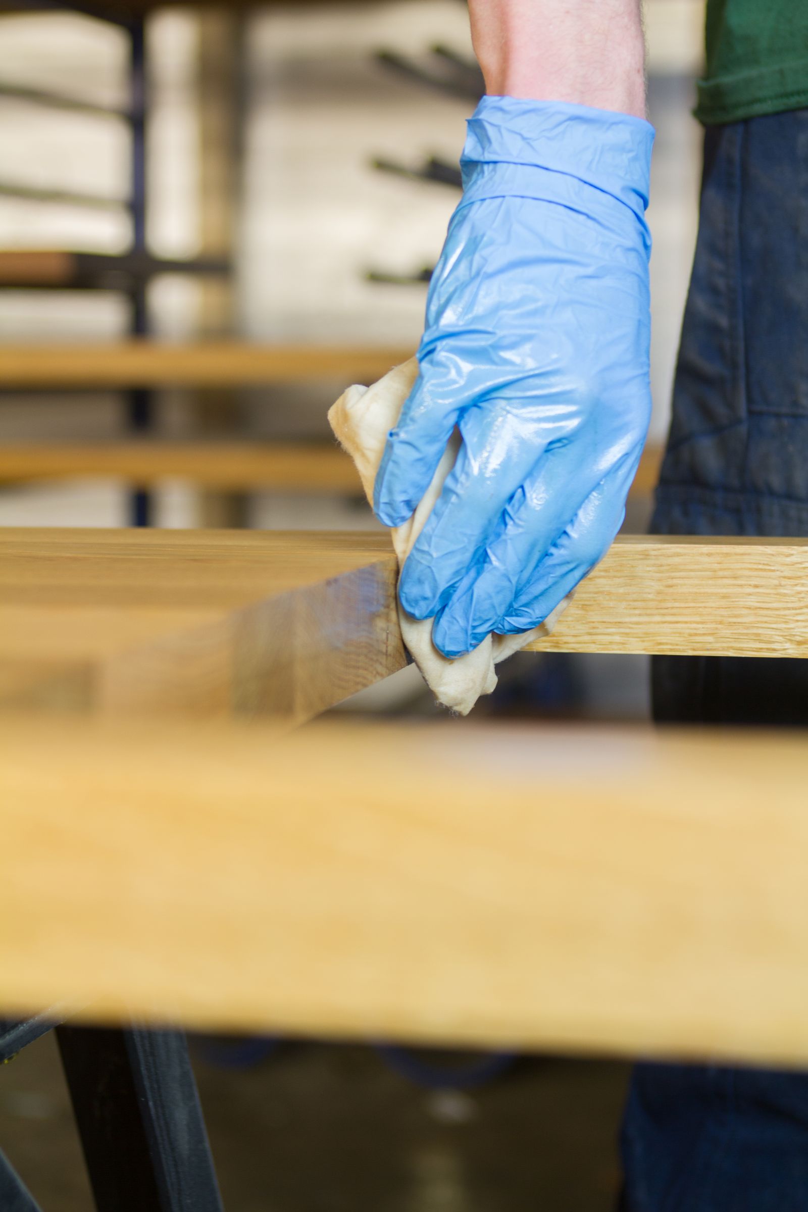 Gloved hand rubbing oil into the edge of an oak worktop with a cloth