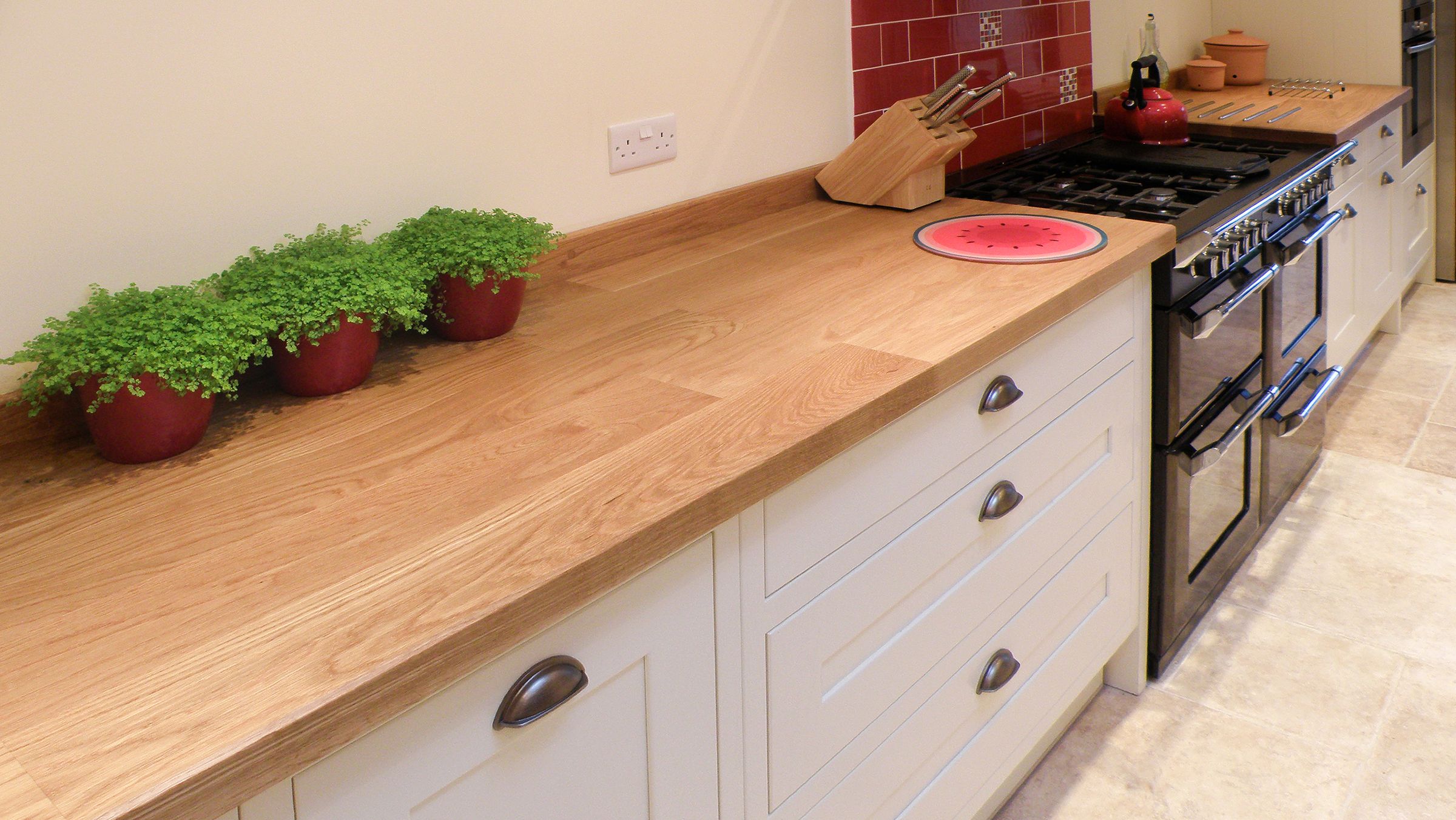 Traditional plank oak worktop in a cream kitchen with range cooker and potted plants