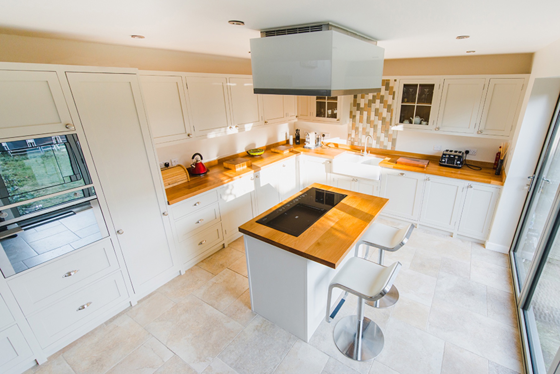 White shaker kitchen with oak worktops, island breakfast bar and inset hob