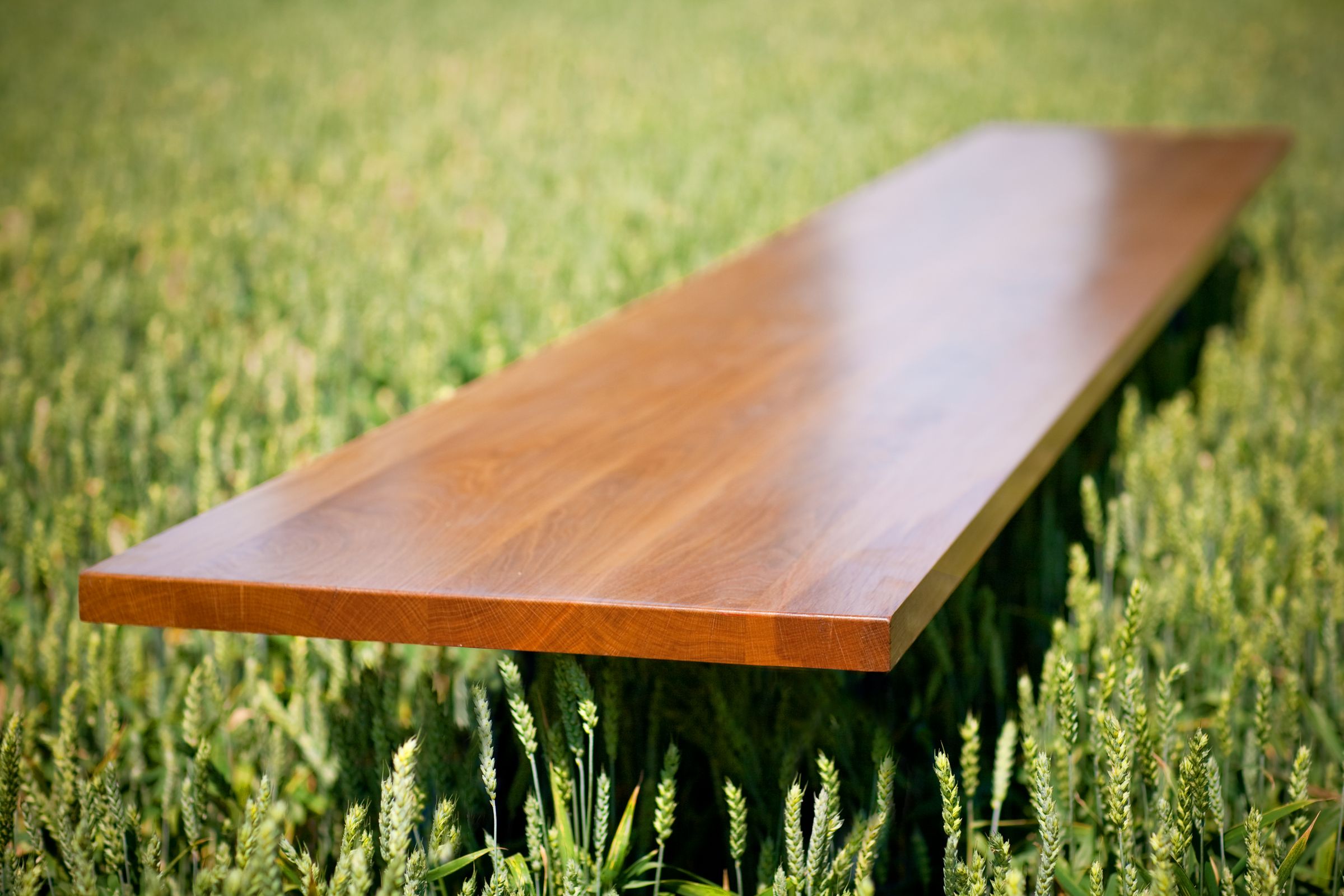 Oiled solid oak worktop resting above a green wheat field