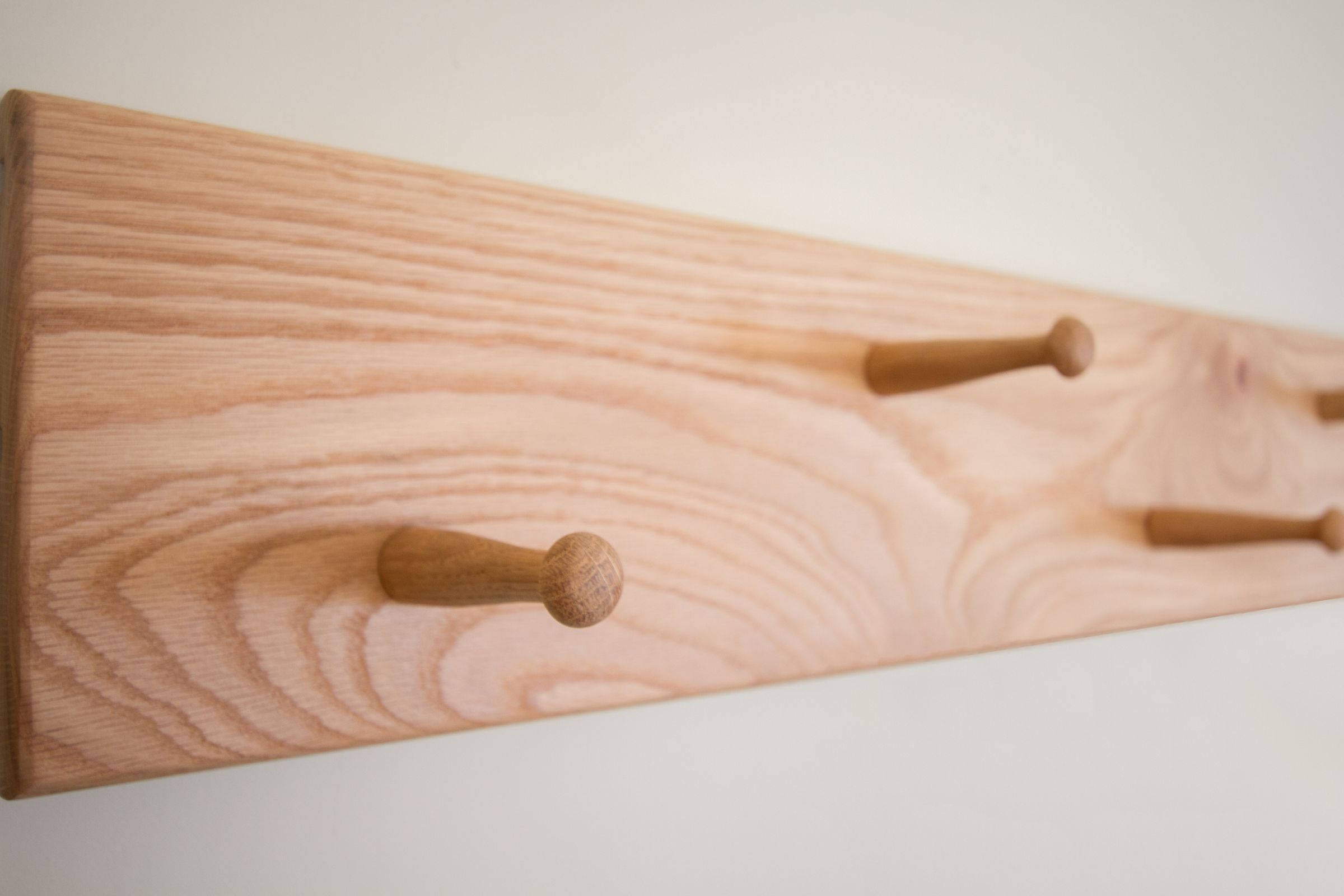 Oak Shaker peg rail with pegs staggered at two heights, seen close up