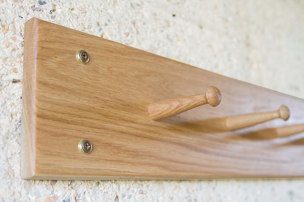 Close-up of turned pegs on an oak Shaker peg rail against a stone wall