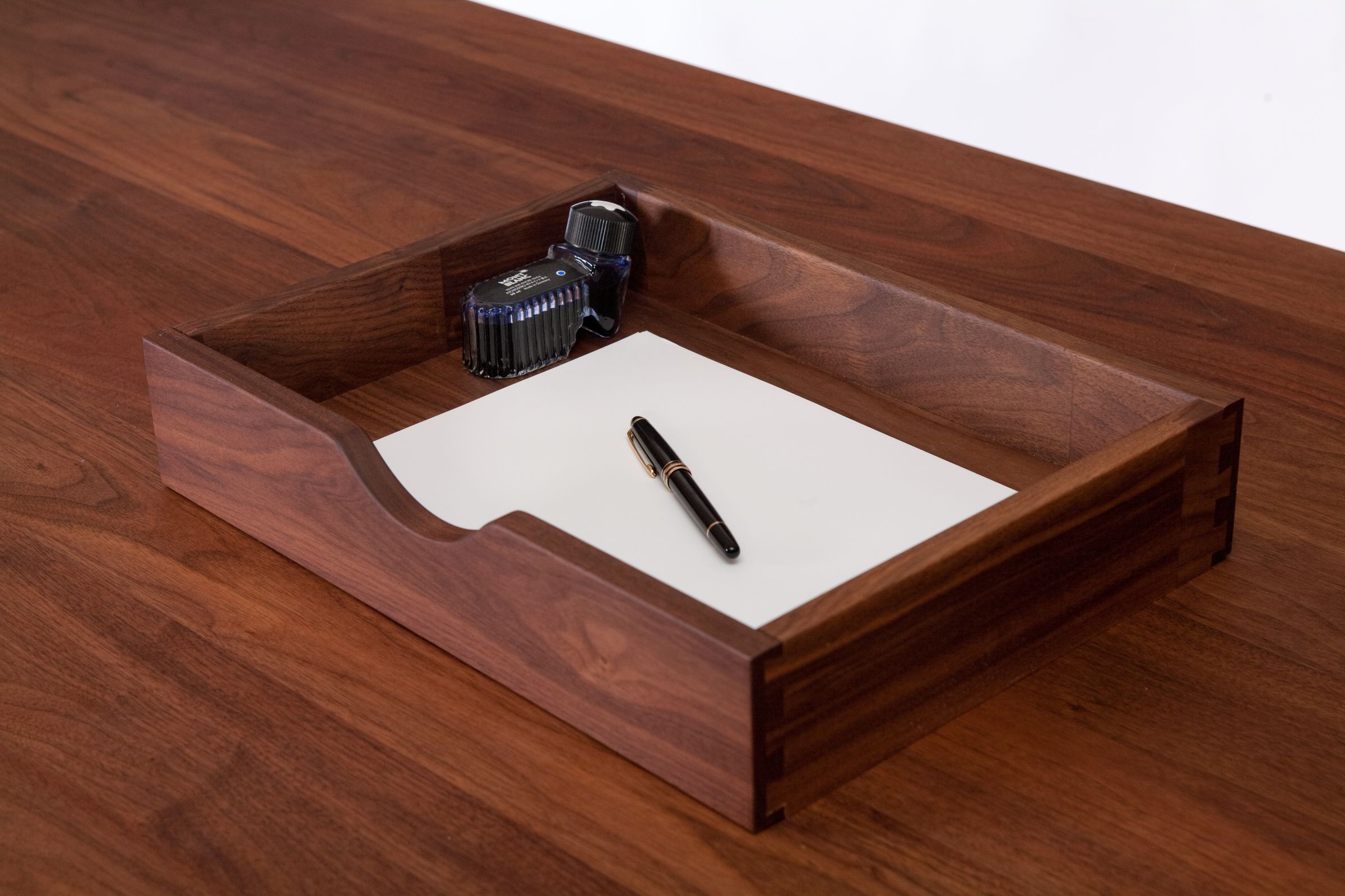 Dovetailed walnut drawer holding paper, a fountain pen and an ink bottle