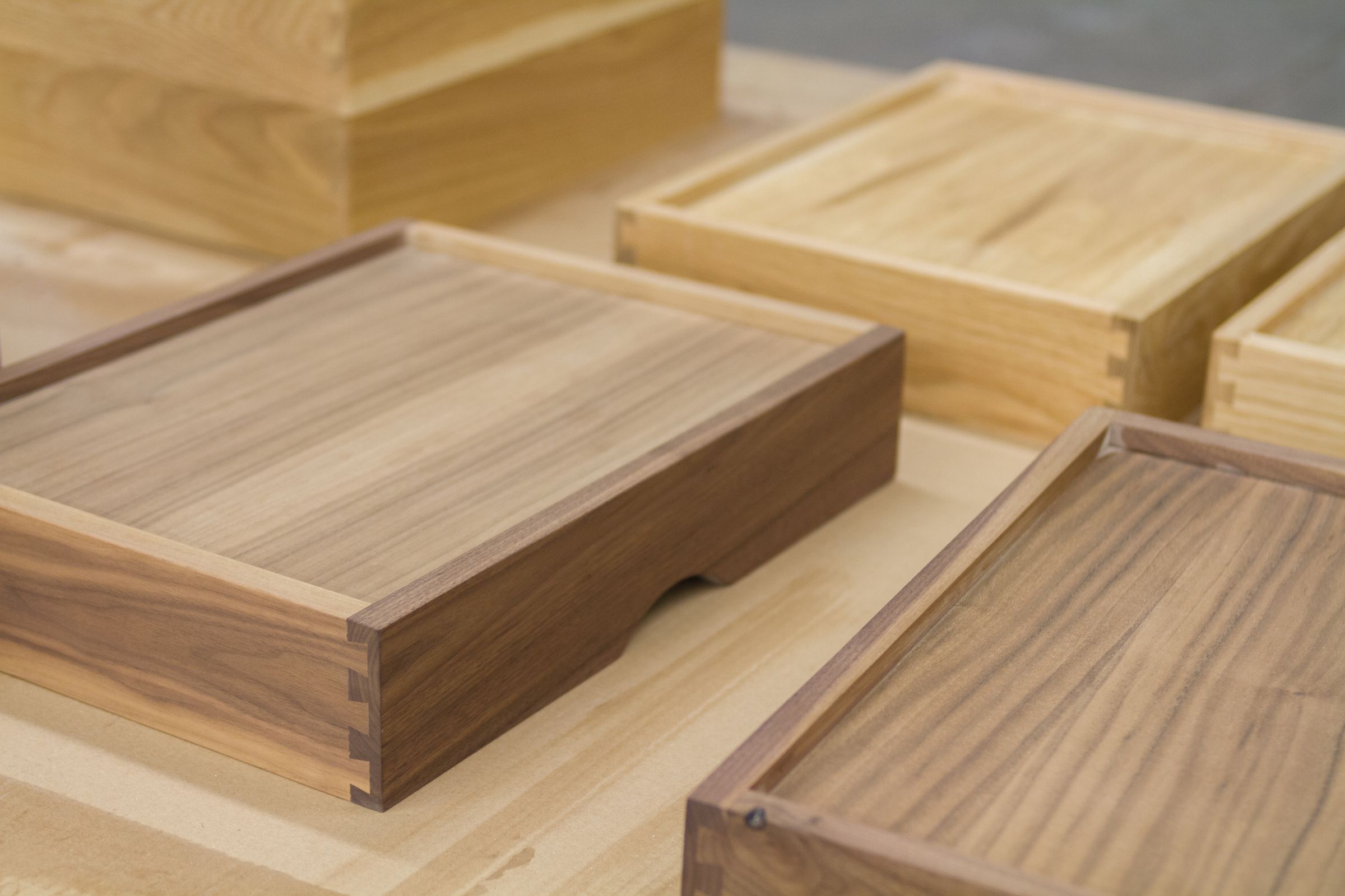 Dovetailed walnut and oak drawer boxes on a workshop bench after final sanding