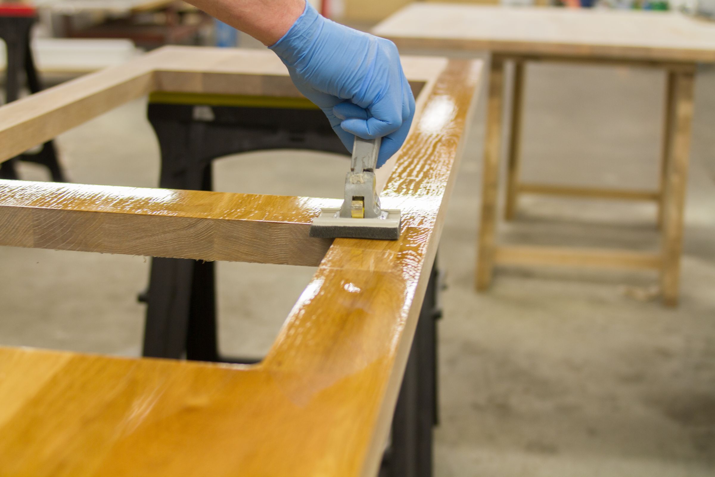 Gloved hand applying nano-coat oil to an oak worktop with a pad applicator