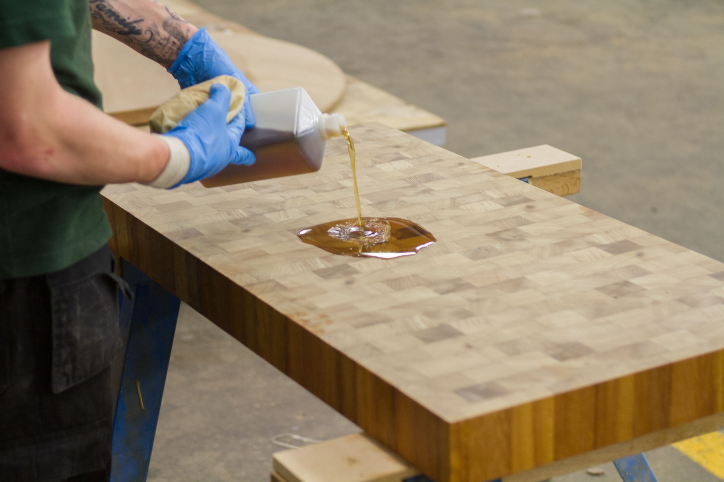 oiling iroko end grain worktop Craftsman pouring the first coat of oil onto an iroko end grain worktop