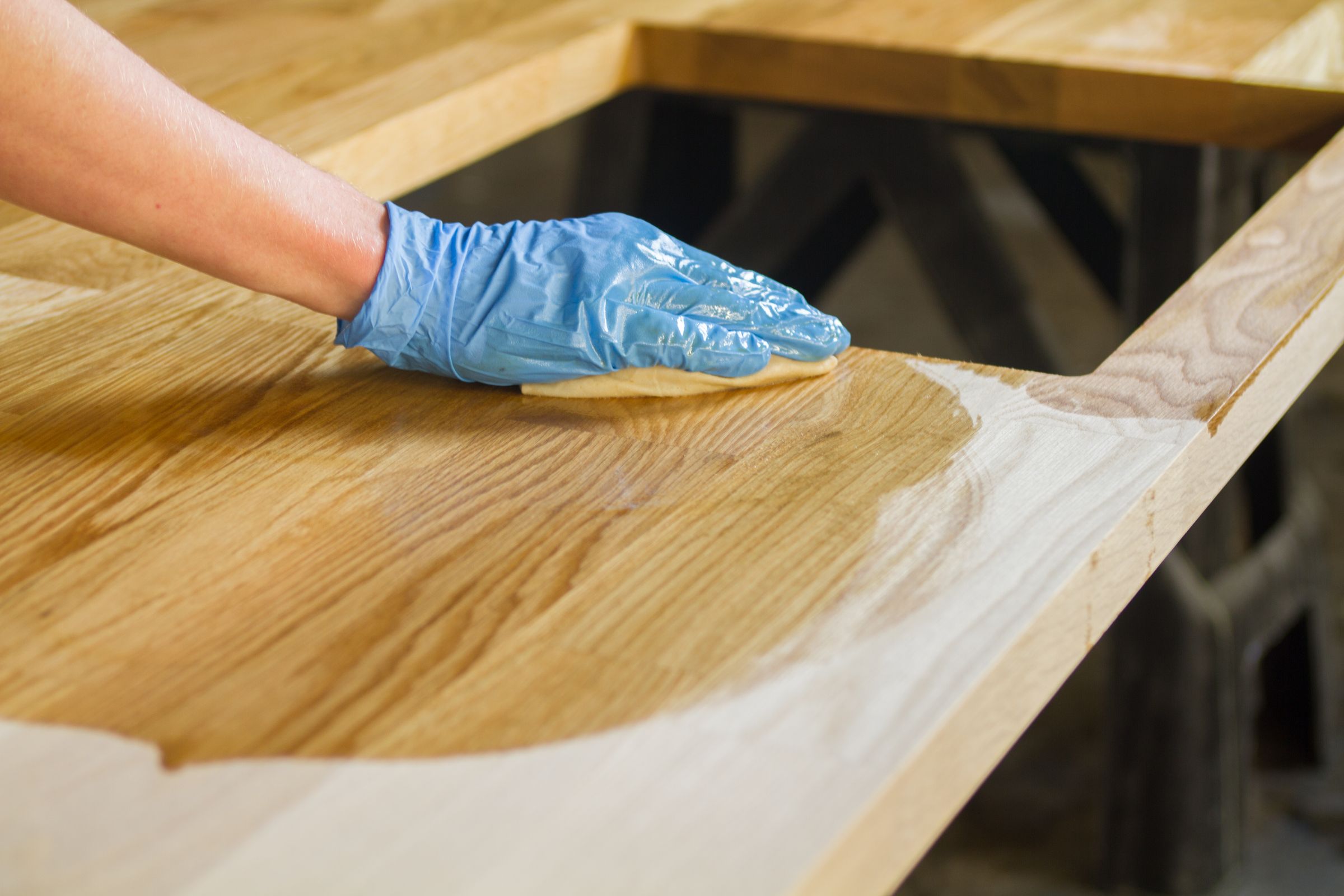 oiling oak worktop Gloved hand wiping the first coat of linseed oil into an oak worktop