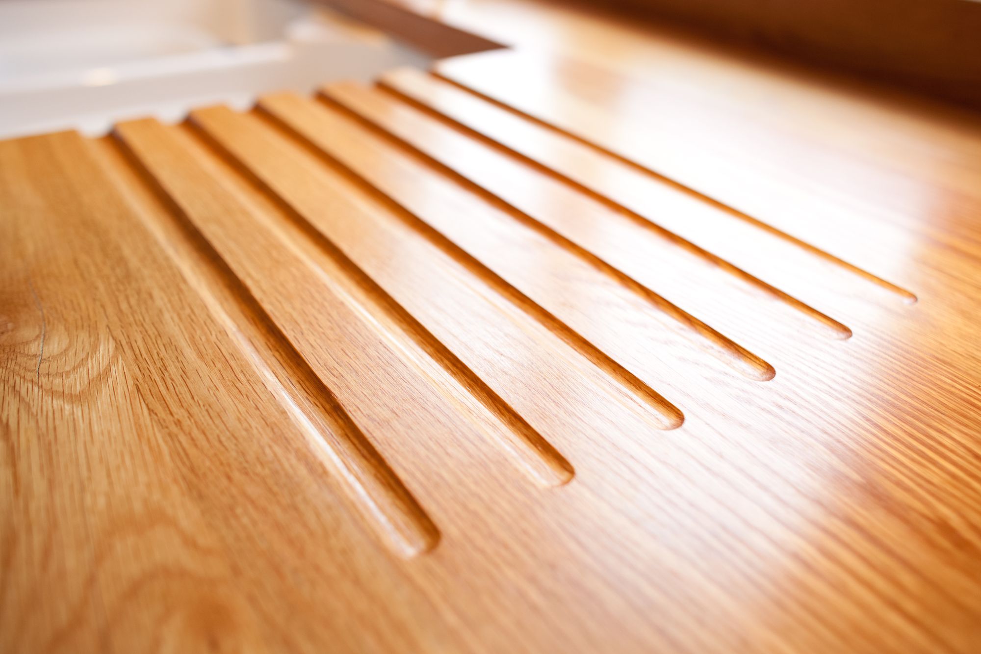 Close-up of routed drainage grooves in an oak worktop beside the sink