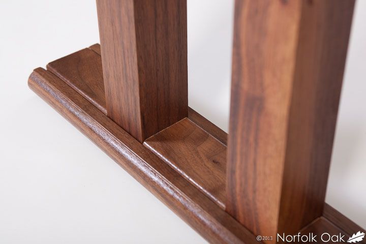 Close-up of walnut table legs joined to a moulded base rail