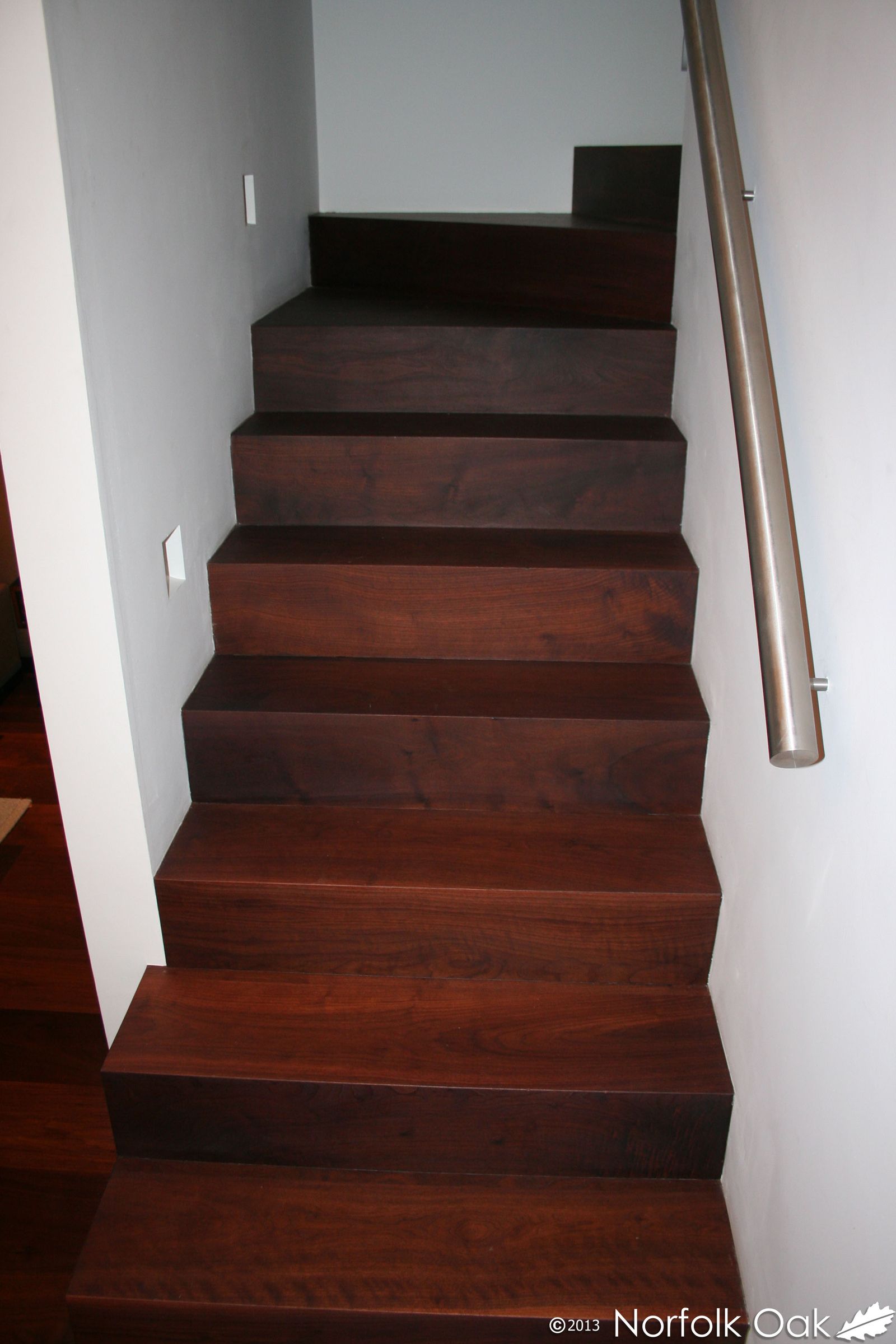 Dark walnut staircase with solid timber treads and stainless steel handrail