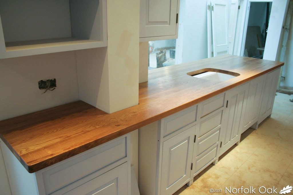 Newly fitted oak worktop with sink cutout on painted cabinets mid-renovation