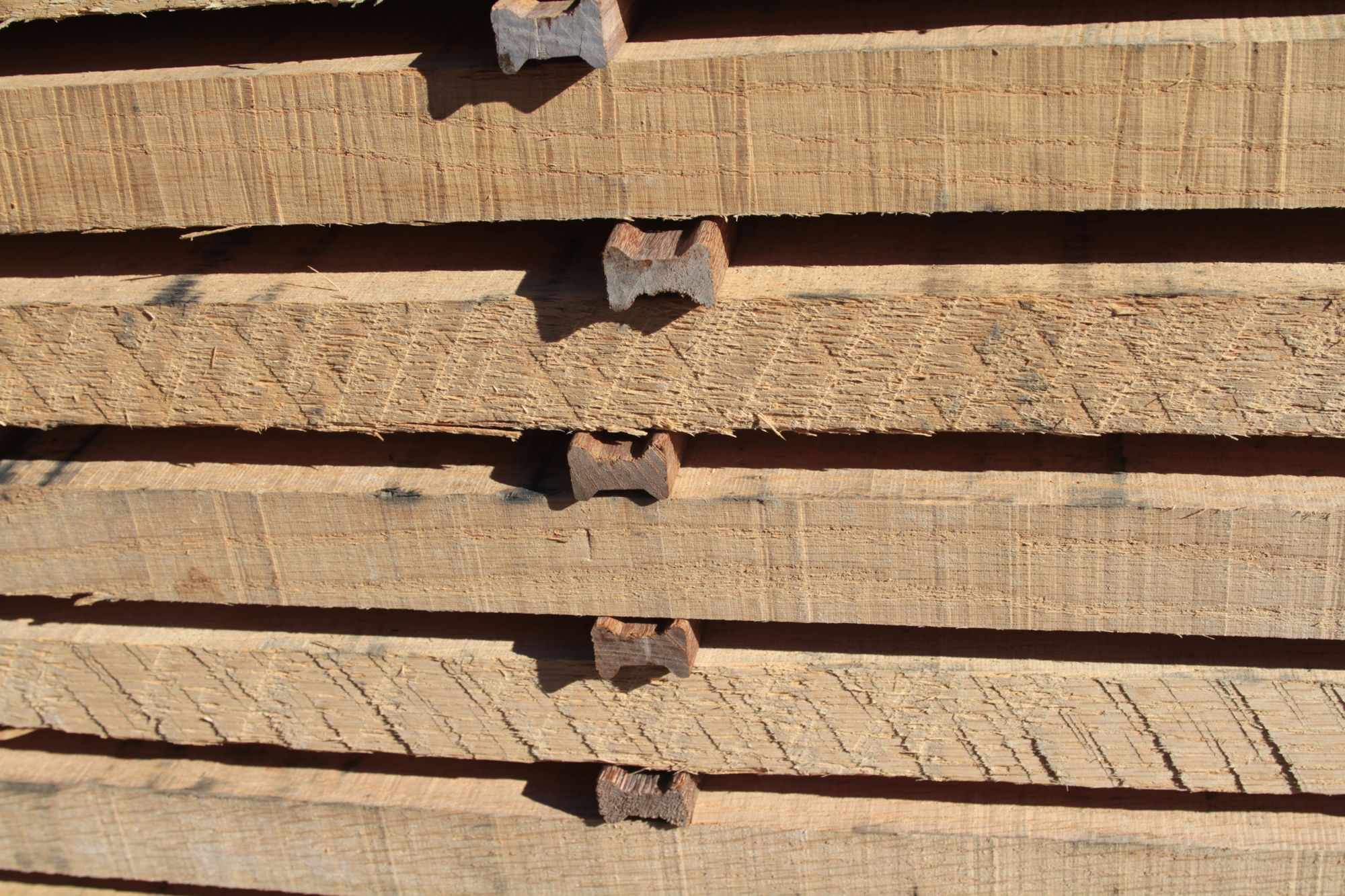 Rough sawn boards stacked with spacer sticks between each layer for air drying