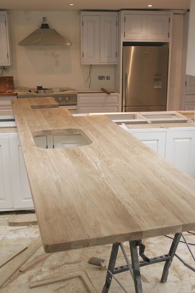 Unfinished oak worktop resting on trestles in a kitchen during installation