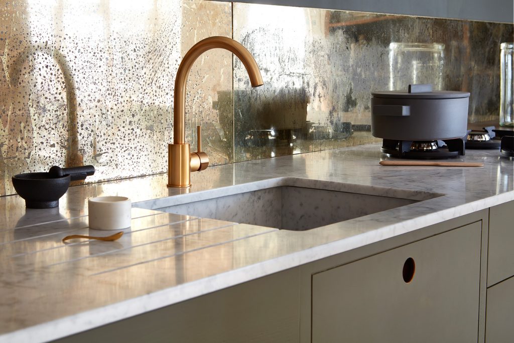 Marble worktop with drainer grooves, brass tap and antique mirrored splashback