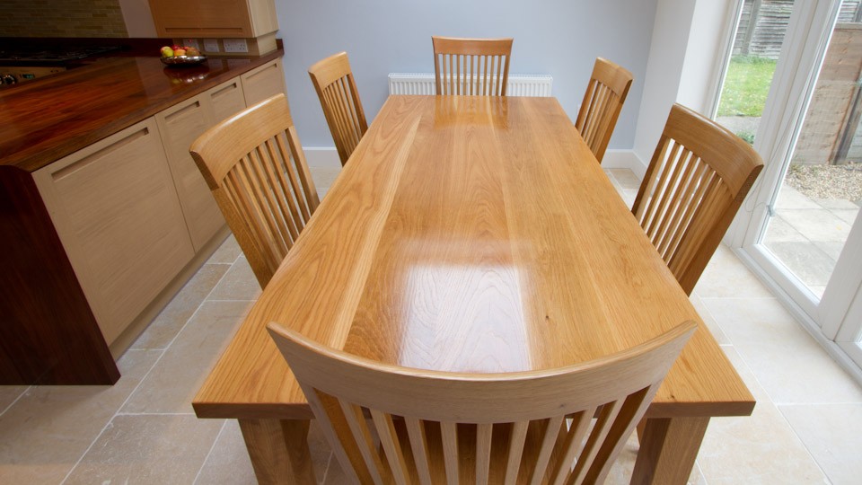 Solid oak dining table with six matching slat-back chairs