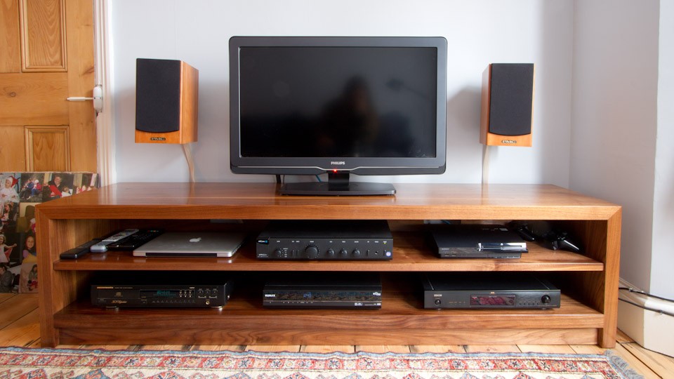 Solid walnut AV unit with open shelves holding a TV, speakers and hi-fi equipment