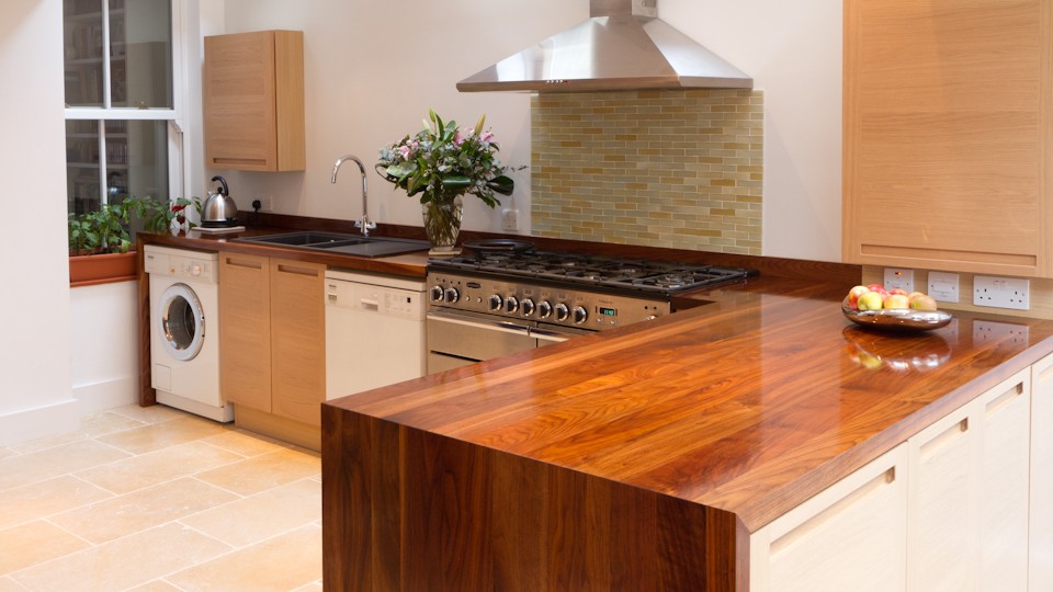 Walnut worktop peninsula with waterfall end panel in a cream kitchen with range cooker